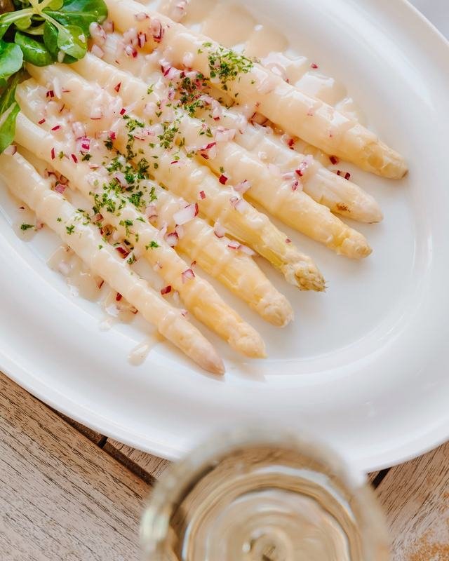 Asperges blanches nappées de sauce, échalotes et fines herbes : un plat de saison de La Mado.